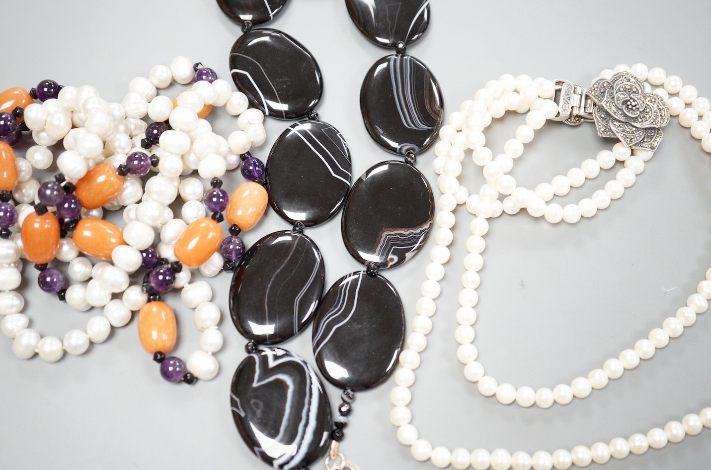 A double strand freshwater pearl necklace, with marcasite set clasp, a banded black agate necklace with 925 clasp and freshwater pearl, amethyst and agate set necklace.